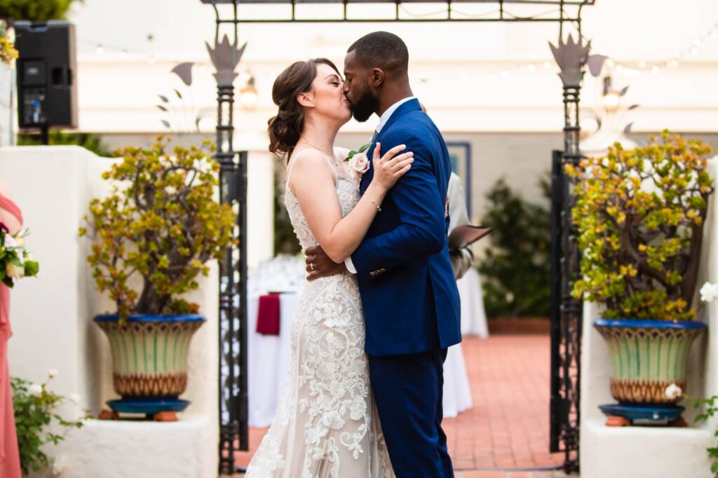 A bride and groom share their first kiss as married partners at the end of their wedding ceremony at Darlington House in La Jolla. Photo by PMC Photography.