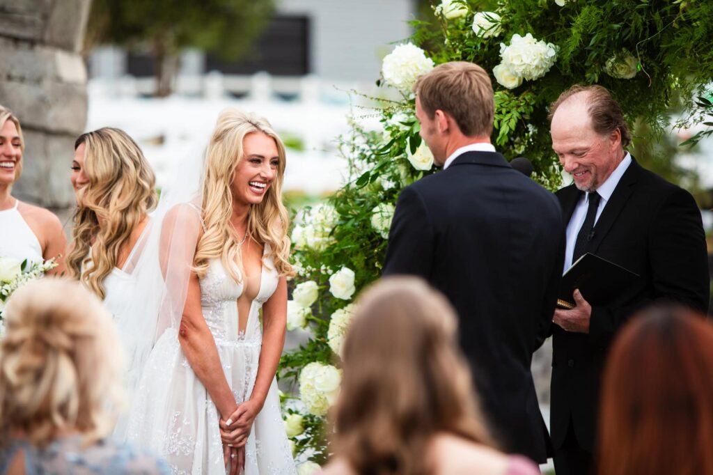 A bride and groom have a light moment of laughter during their elegant wedding ceremony. Photo by PMC Photography.