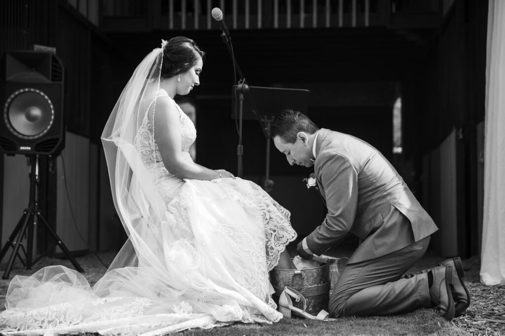 A bride and groom partake in the the Catholic ritual of the washing of the feet during their emotional wedding ceremony. Photo by PMC Photography.