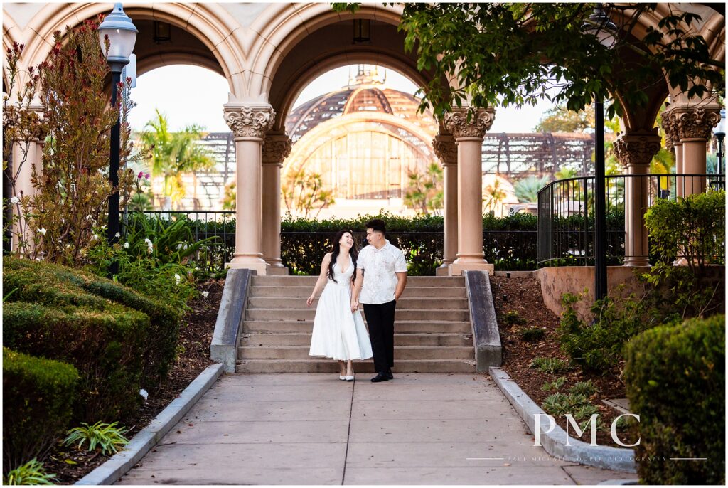 A couple in white takes autumn engagement photos at Balboa Park in the morning.