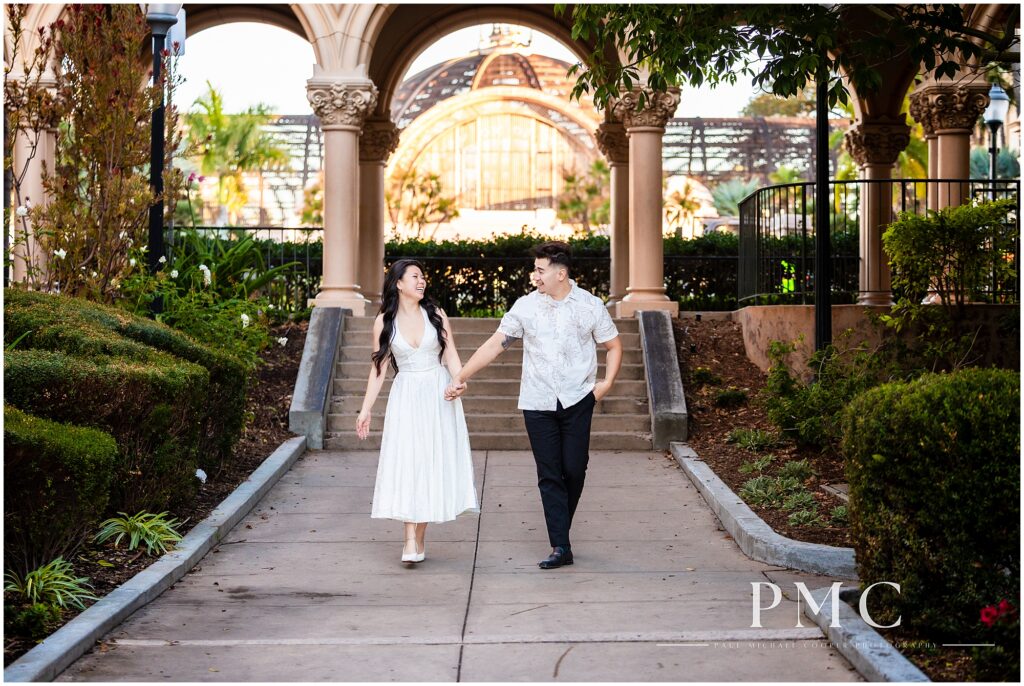 A couple in white takes autumn engagement photos at Balboa Park in the morning.
