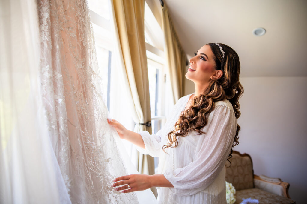 A bride getting ready looks at her wedding dress before putting it on for her wedding at the Newhall Mansion in Piru, Southern California.