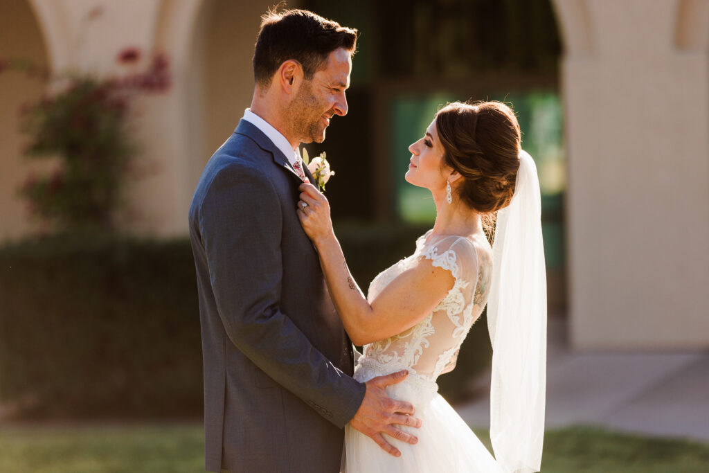 Bride adjusting groom's boutonniere in golden hour light during a Southern California wedding portrait session.